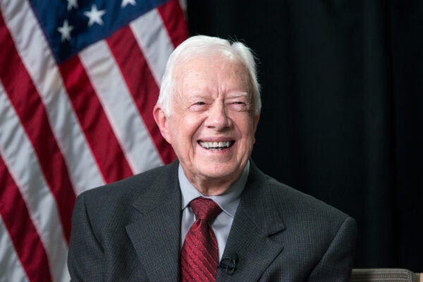 President Jimmy Carter smiles with American flag behind him.