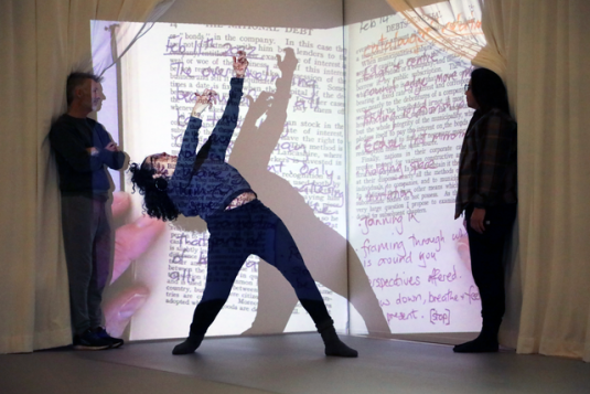 person dancing in front of a projection of a book on a wall