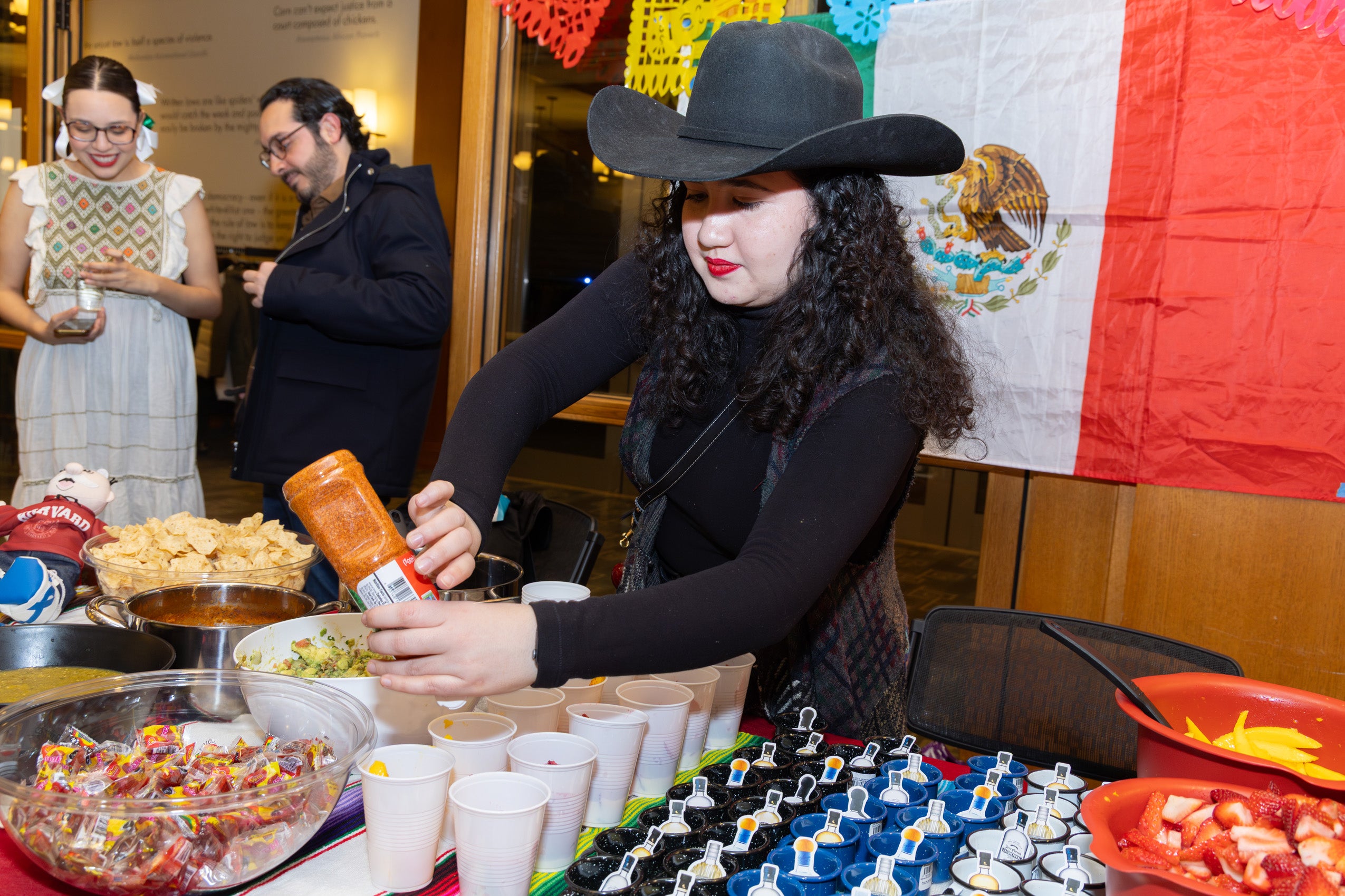 A woman wearing a black hat prepares food at a table.