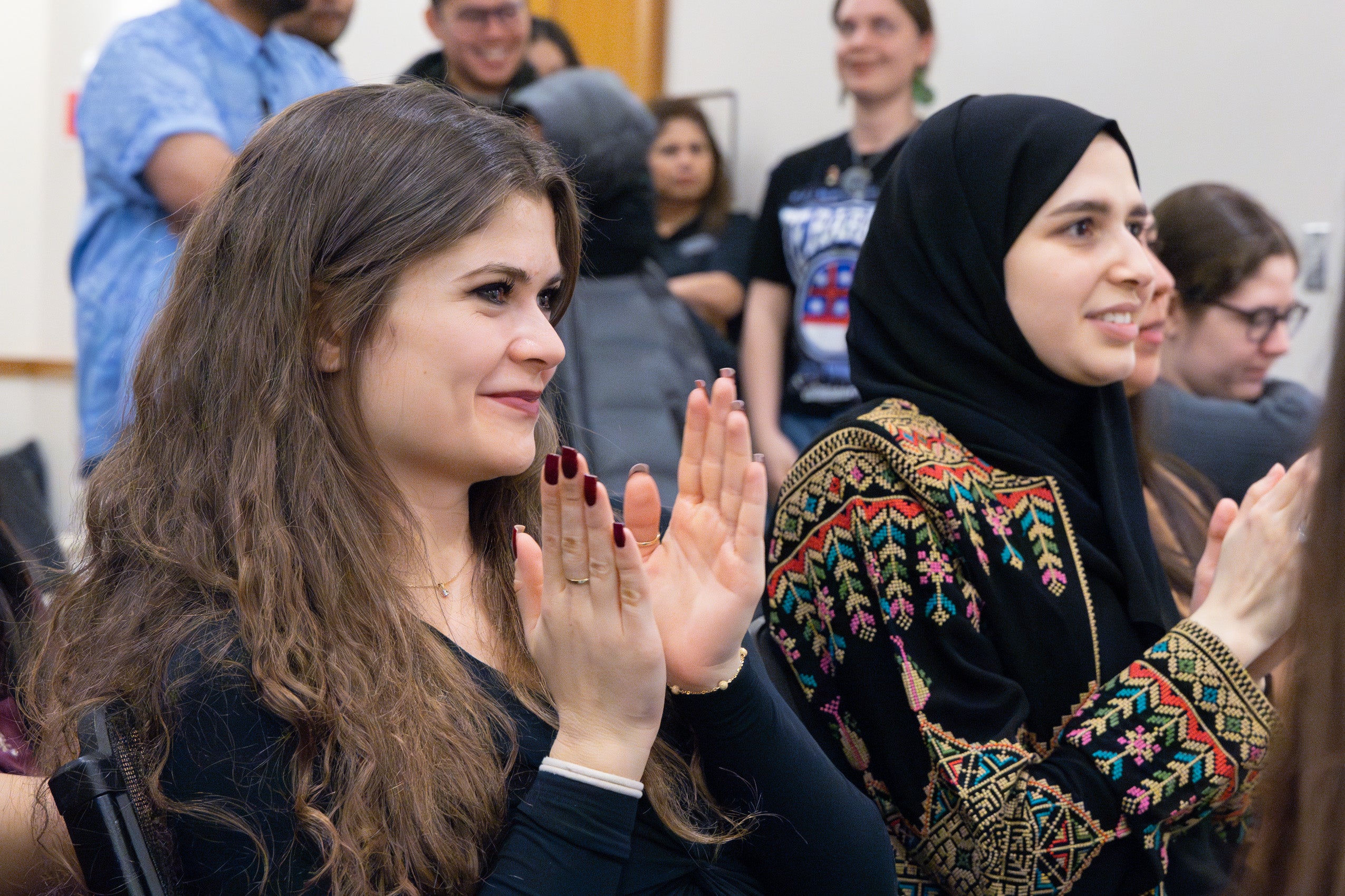 Two students in an audience clap.
