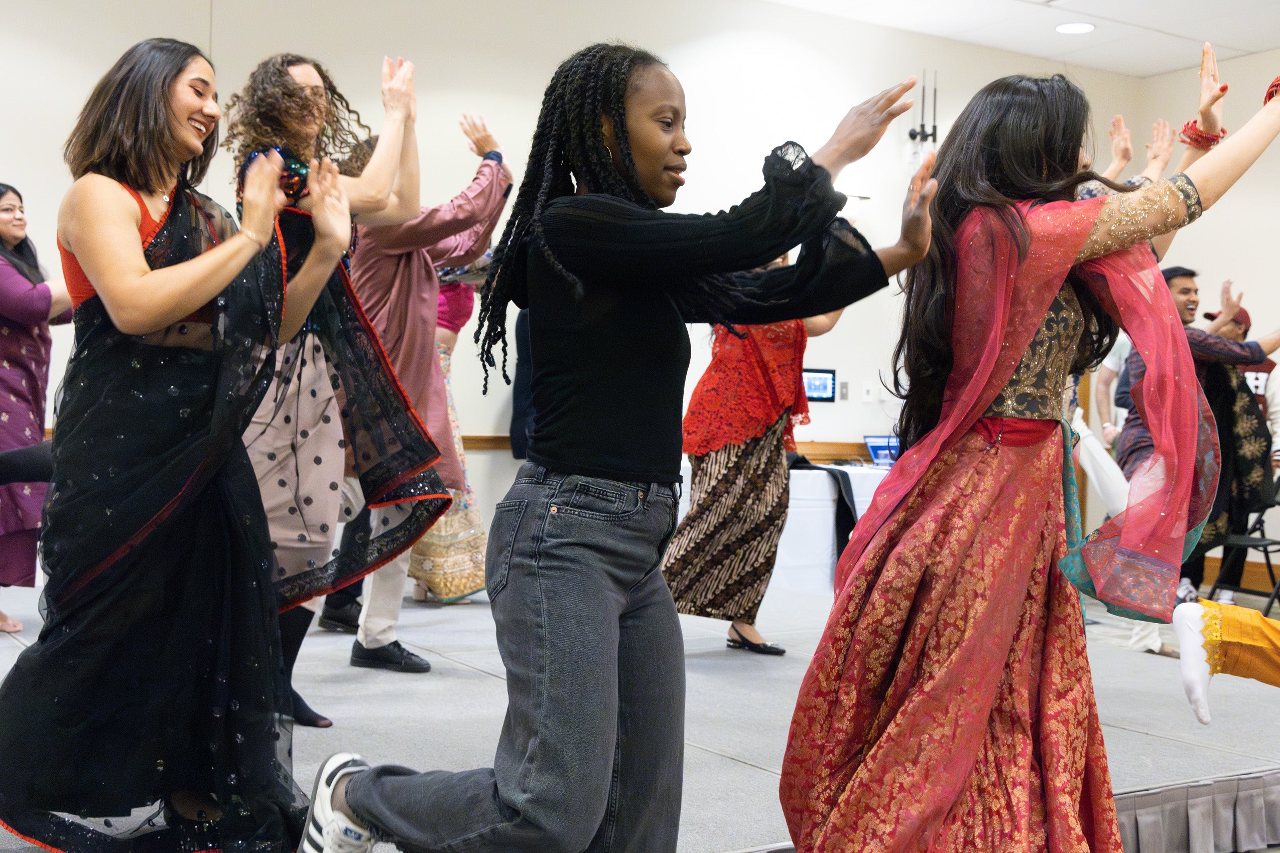 Several students in a line follow the dance moves of a fellow student at an international party.