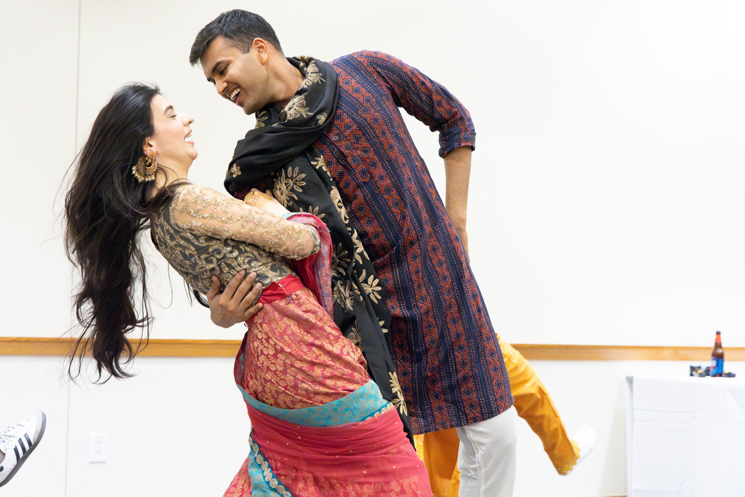 A man and woman perform a dance on stage wearing clothing from their homeland.