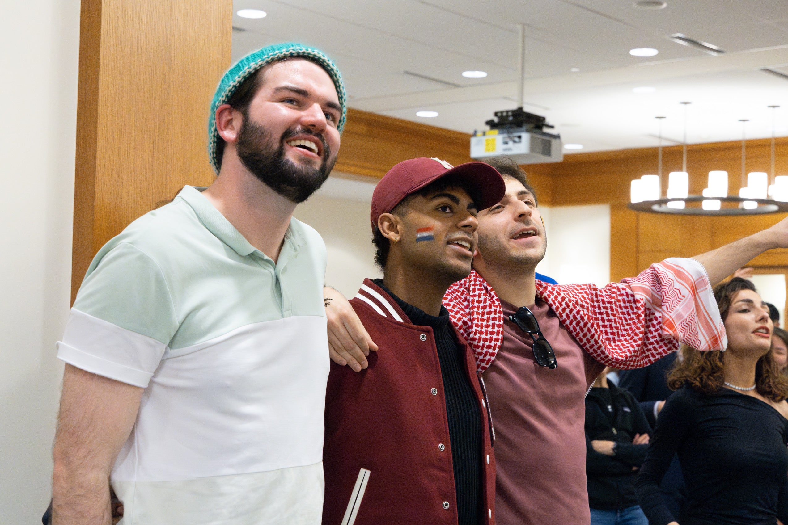 Three men in the audience of the international party sing along with the performers.