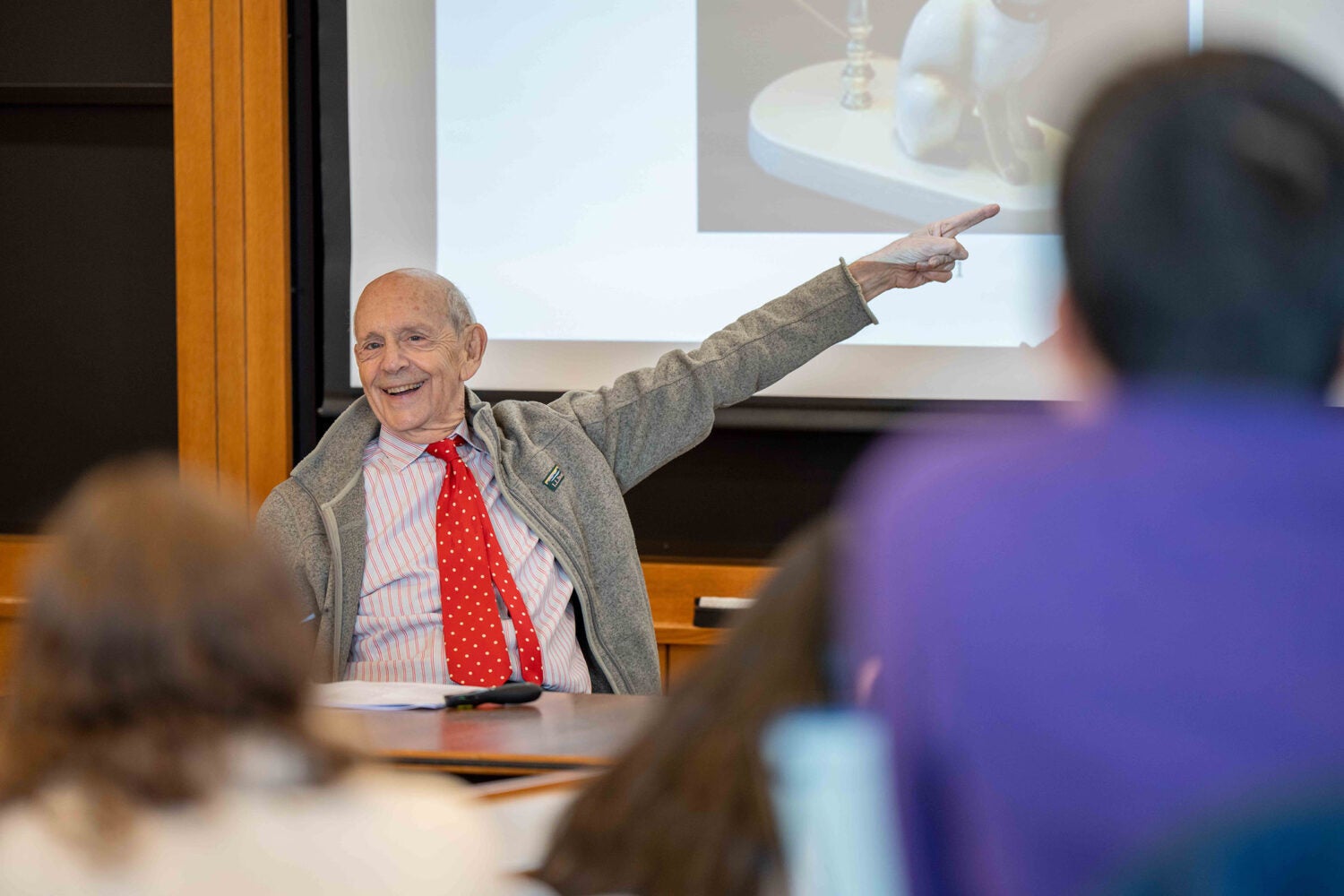 Stephen Breyer smiling and pointing toward a projected image during class.