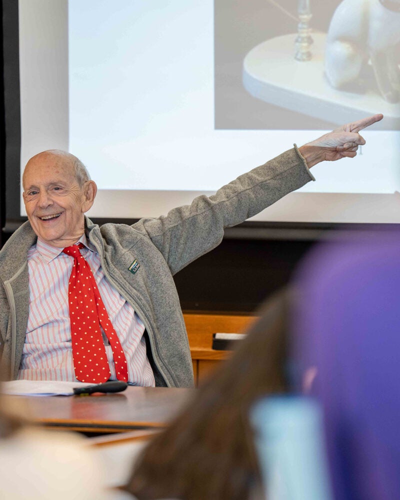 Stephen Breyer smiling and pointing toward a projected image during class.