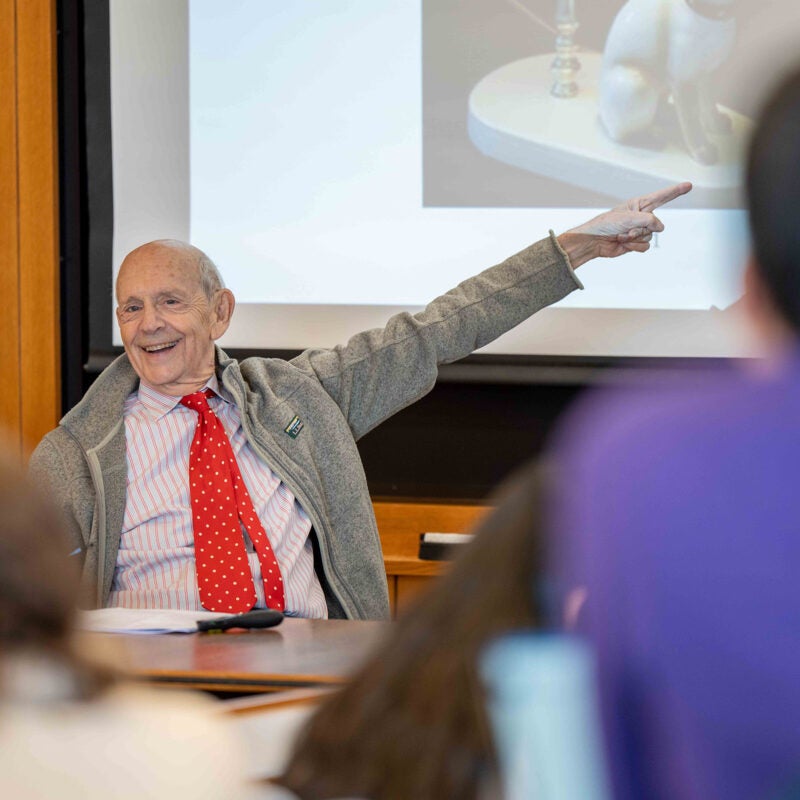 Stephen Breyer smiling and pointing toward a projected image during class.