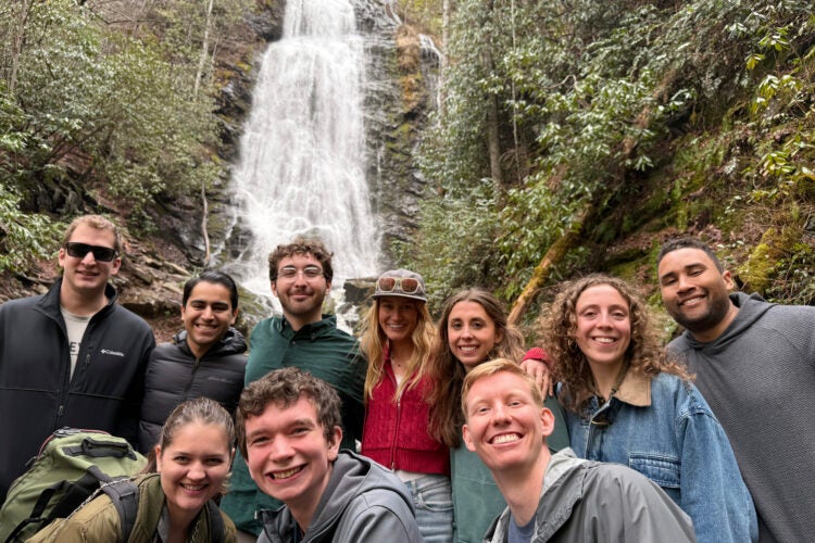 Group of students posing in front of a waterfaul