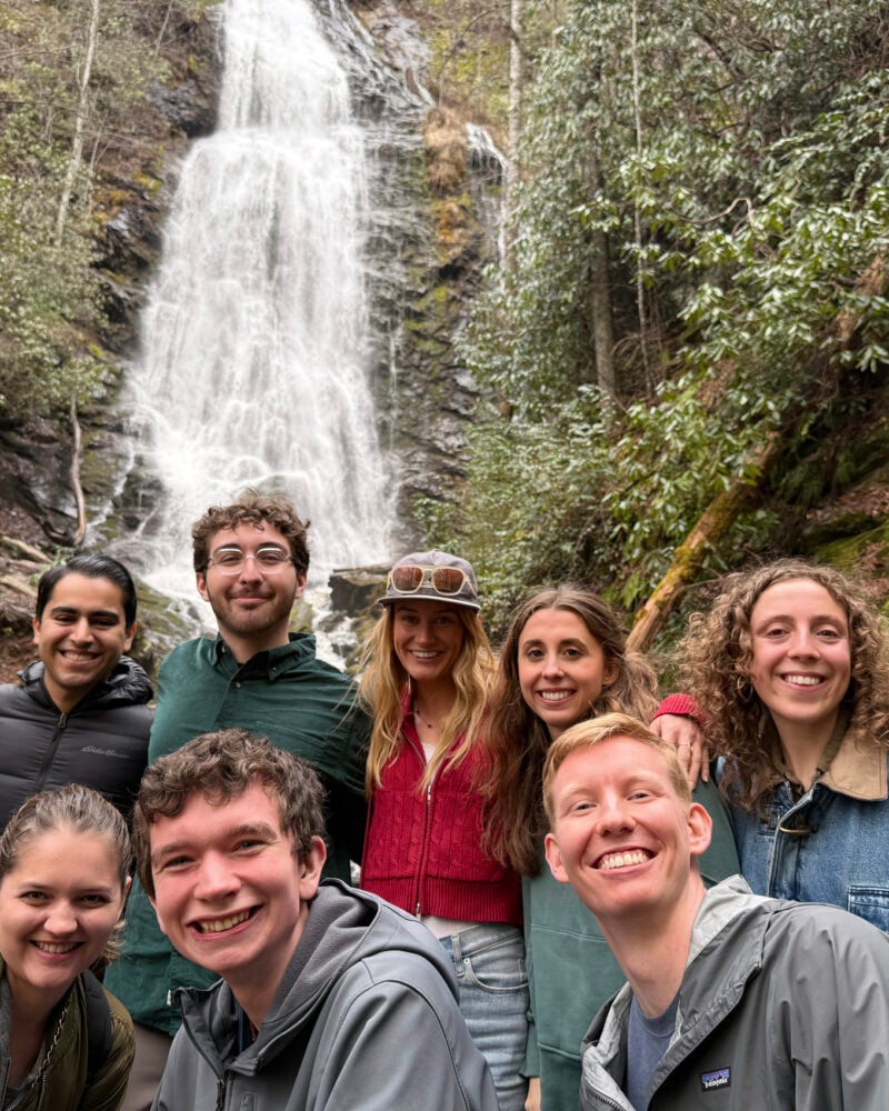 Group of students posing in front of a waterfaul
