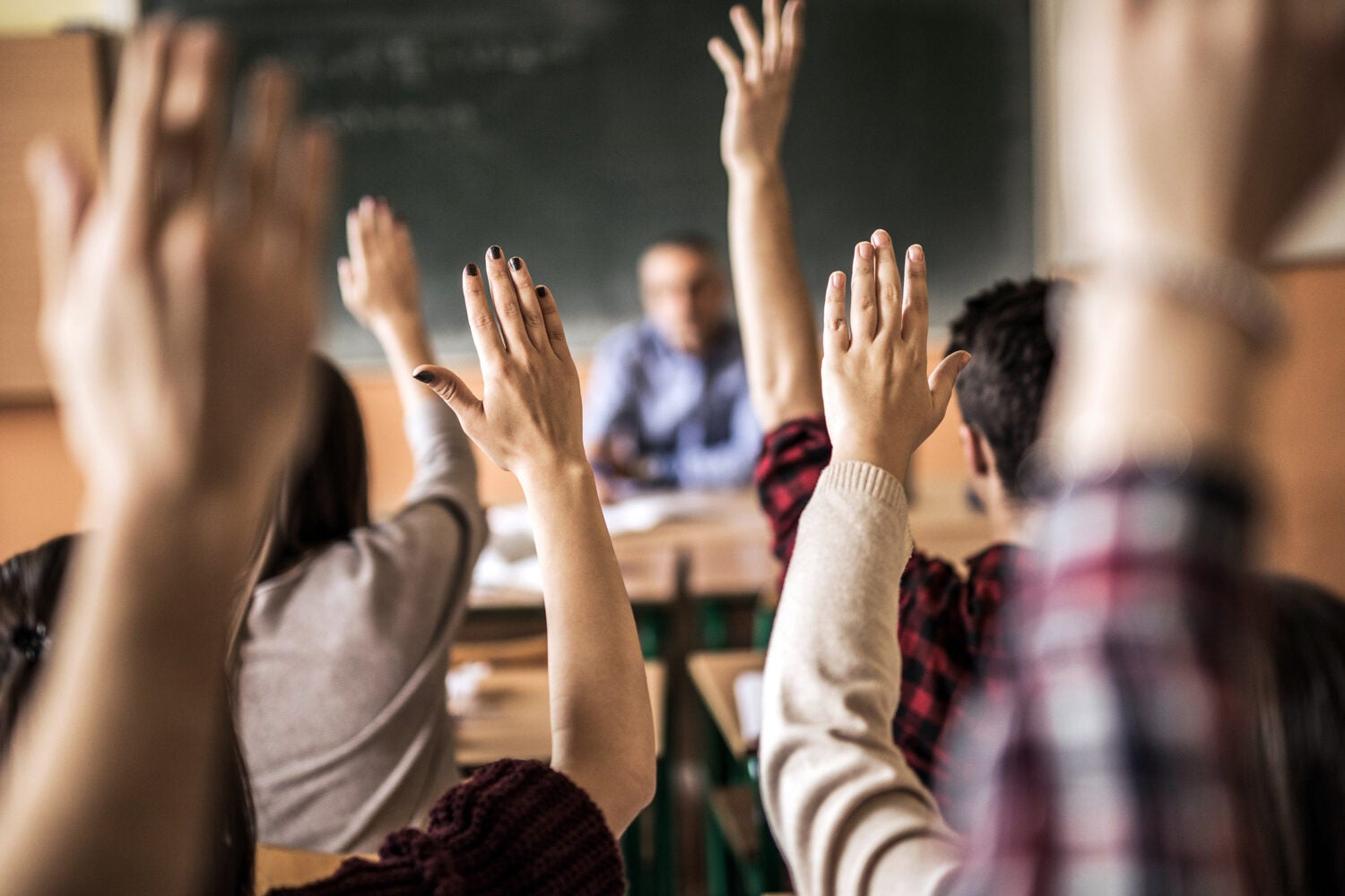 Group of students raising hands.