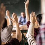 Group of students raising hands.