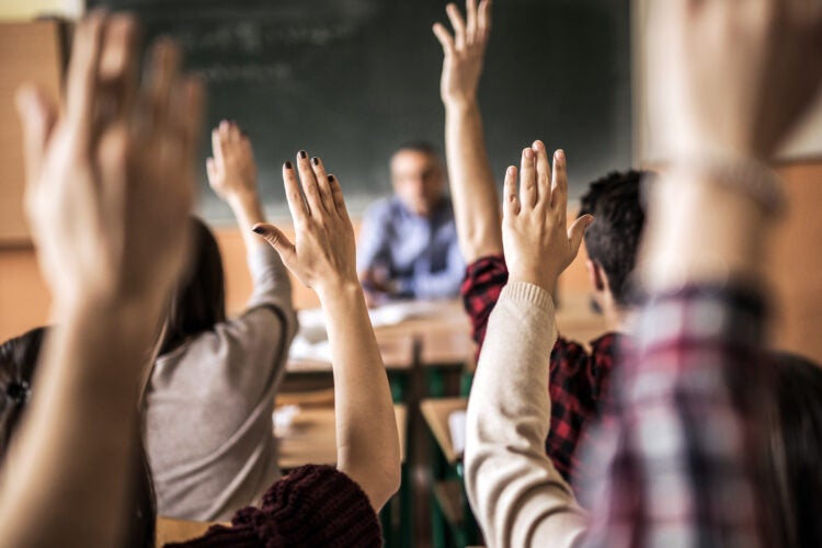 Group of students raising hands.
