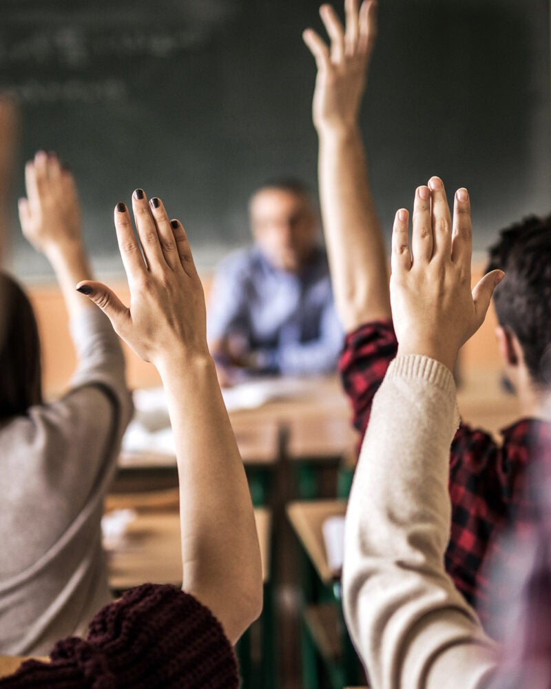 Group of students raising hands.