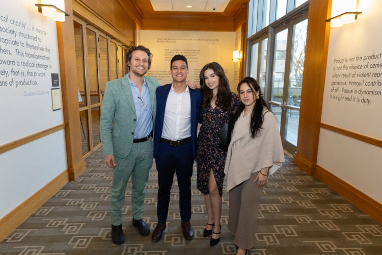Four people standing together smiling