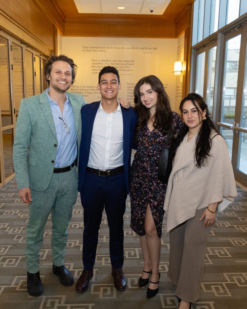 Four people standing together smiling