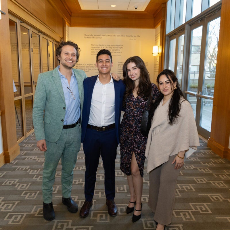 Four people standing together smiling