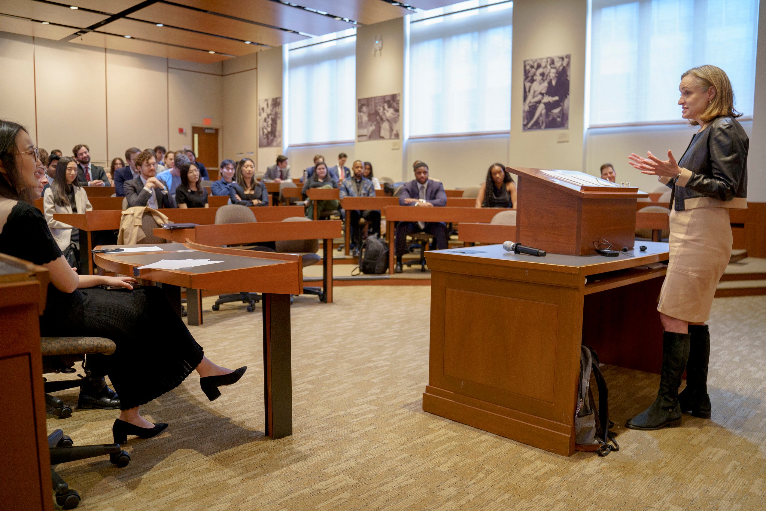 A woman addesses a room of people in a classroom.