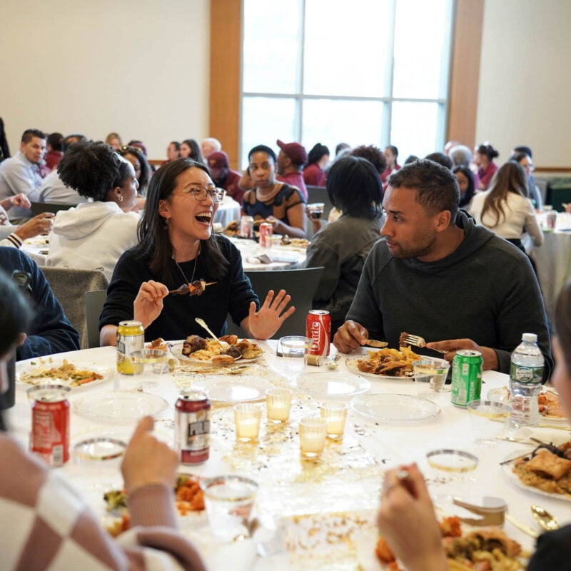 Dinner attendees smiling and laughing in conversation.