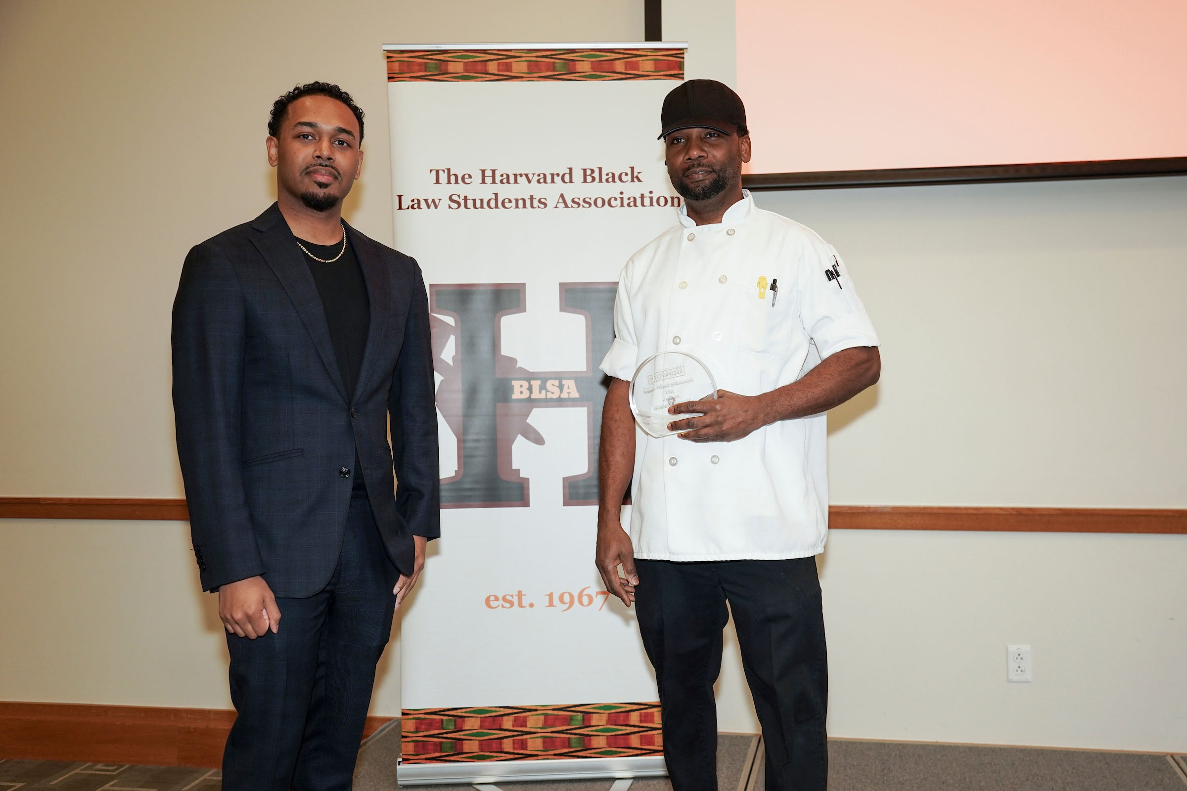 Rehan Staton poses with an awardee onstage.