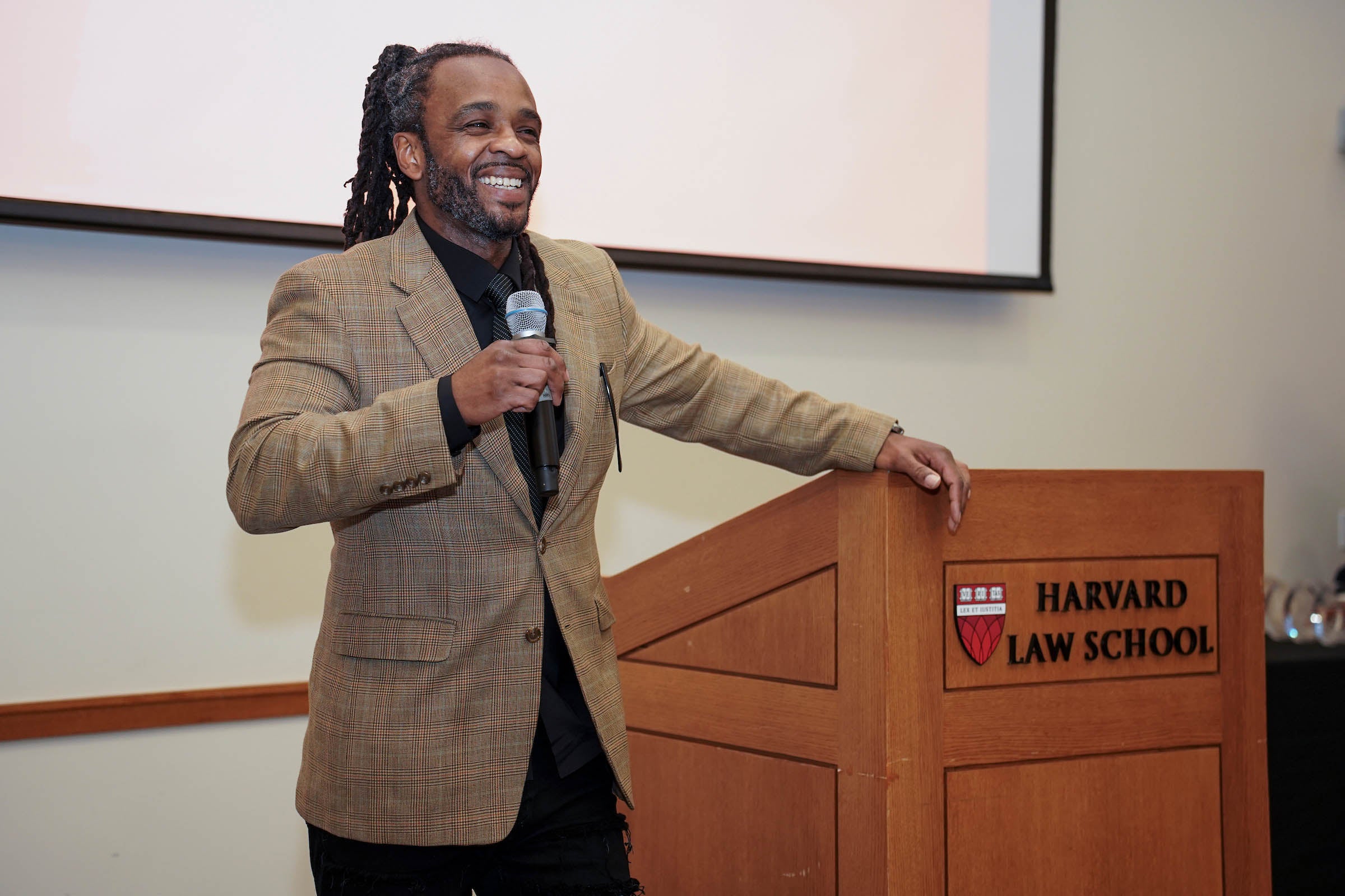 Host Brione Merchant addresses the audience smiling.