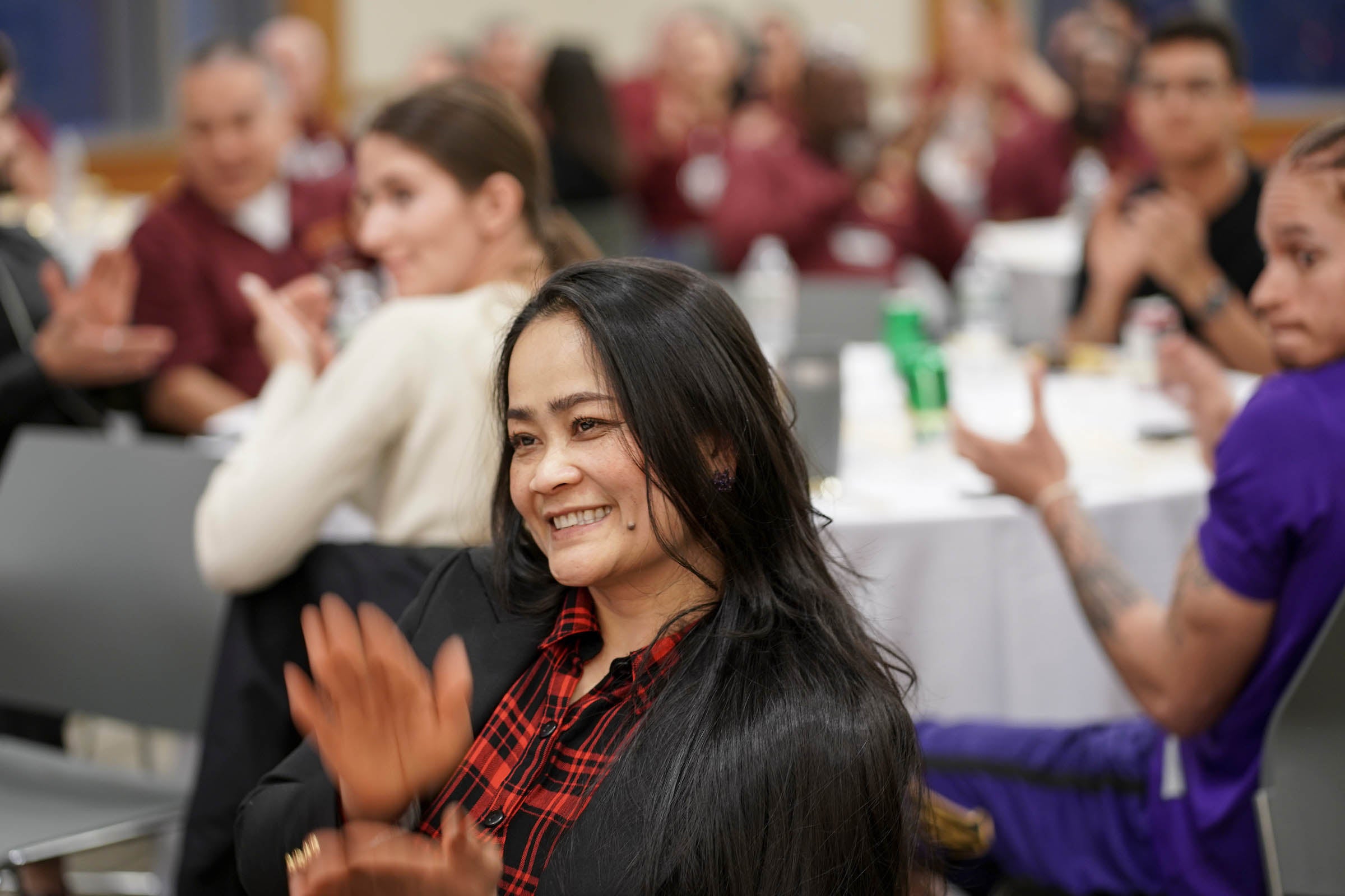 A woman smiles and applauds.
