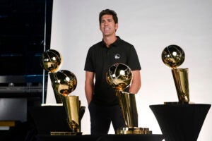 Bob Myers posing with NBA Championship trophies.