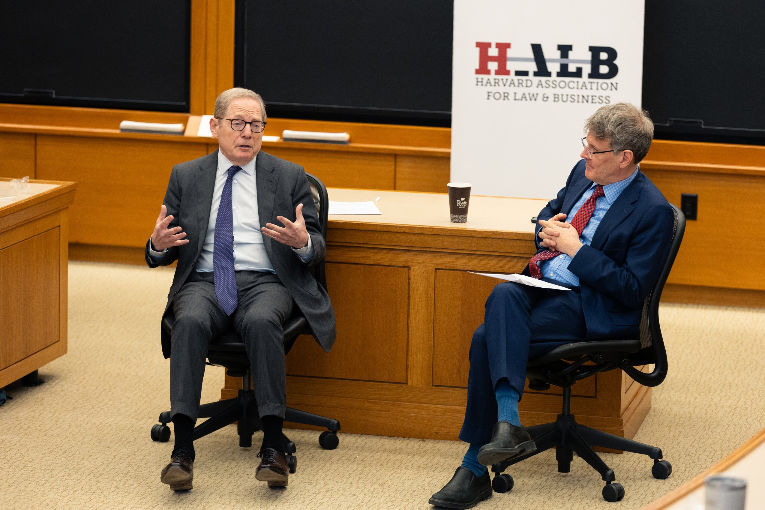 John Coates and John Finley in conversation in a classroom.