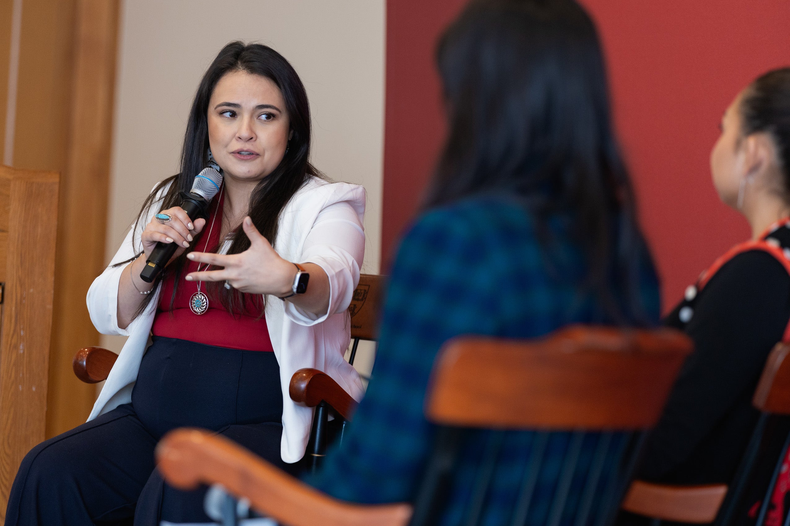 A woman holding a microphone speaks on a panel.