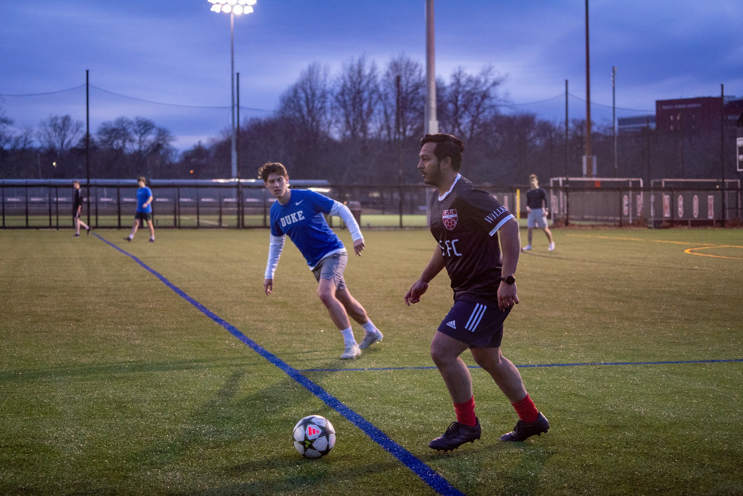 Two men play soccer on a field.