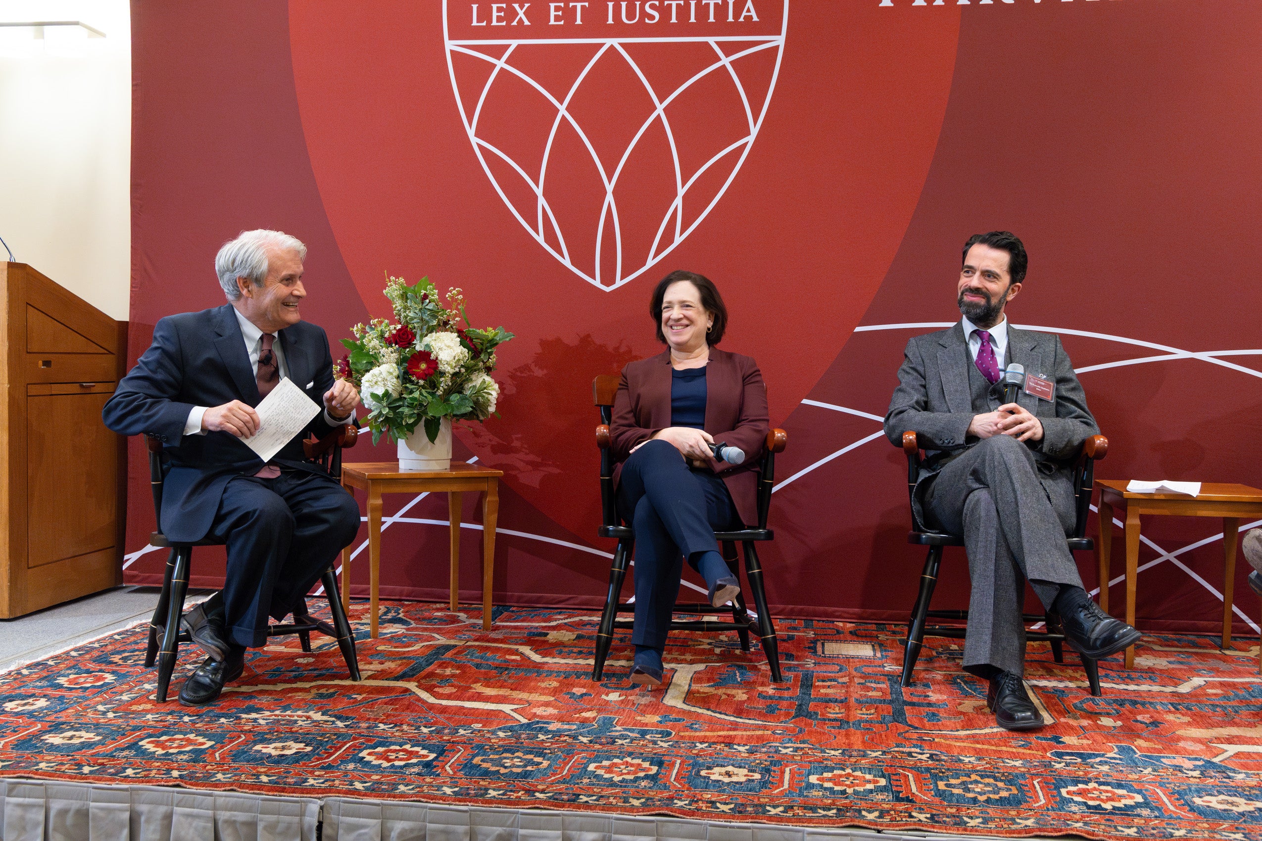 Three panelists speak on a stage.