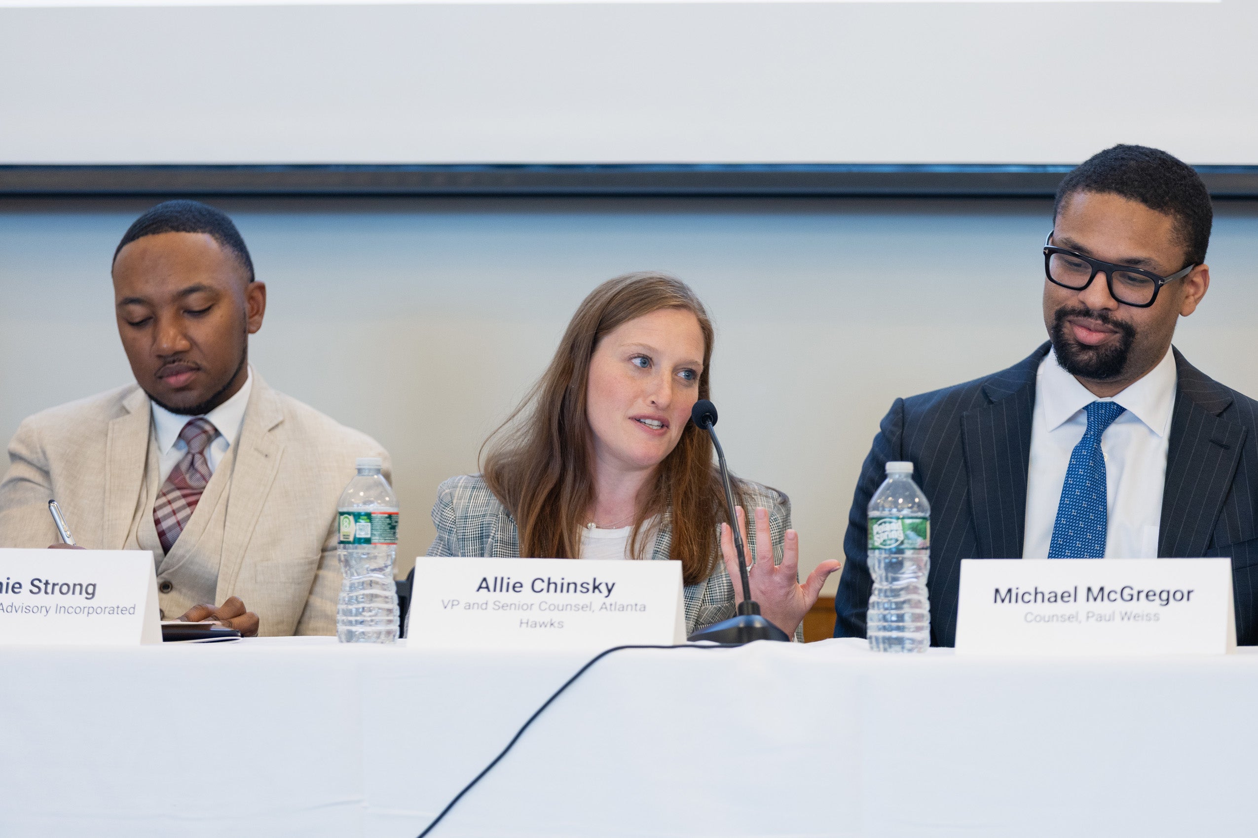 Three panels sit on a panel at an event.