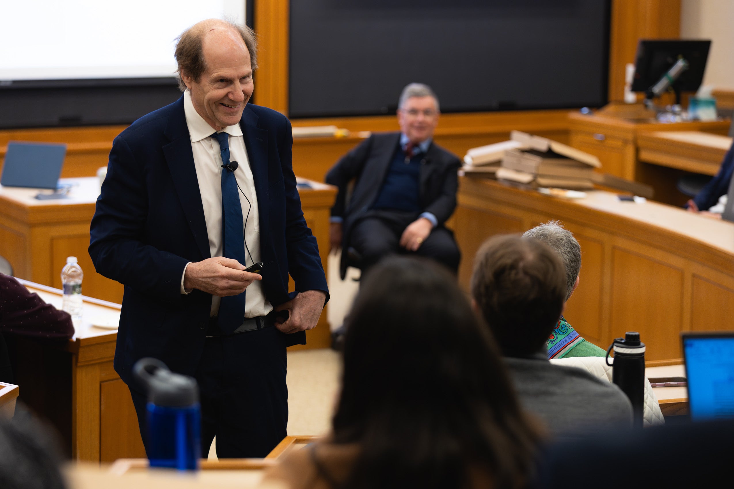 Cass Sunstein speaks with a student in a classroom during an event.