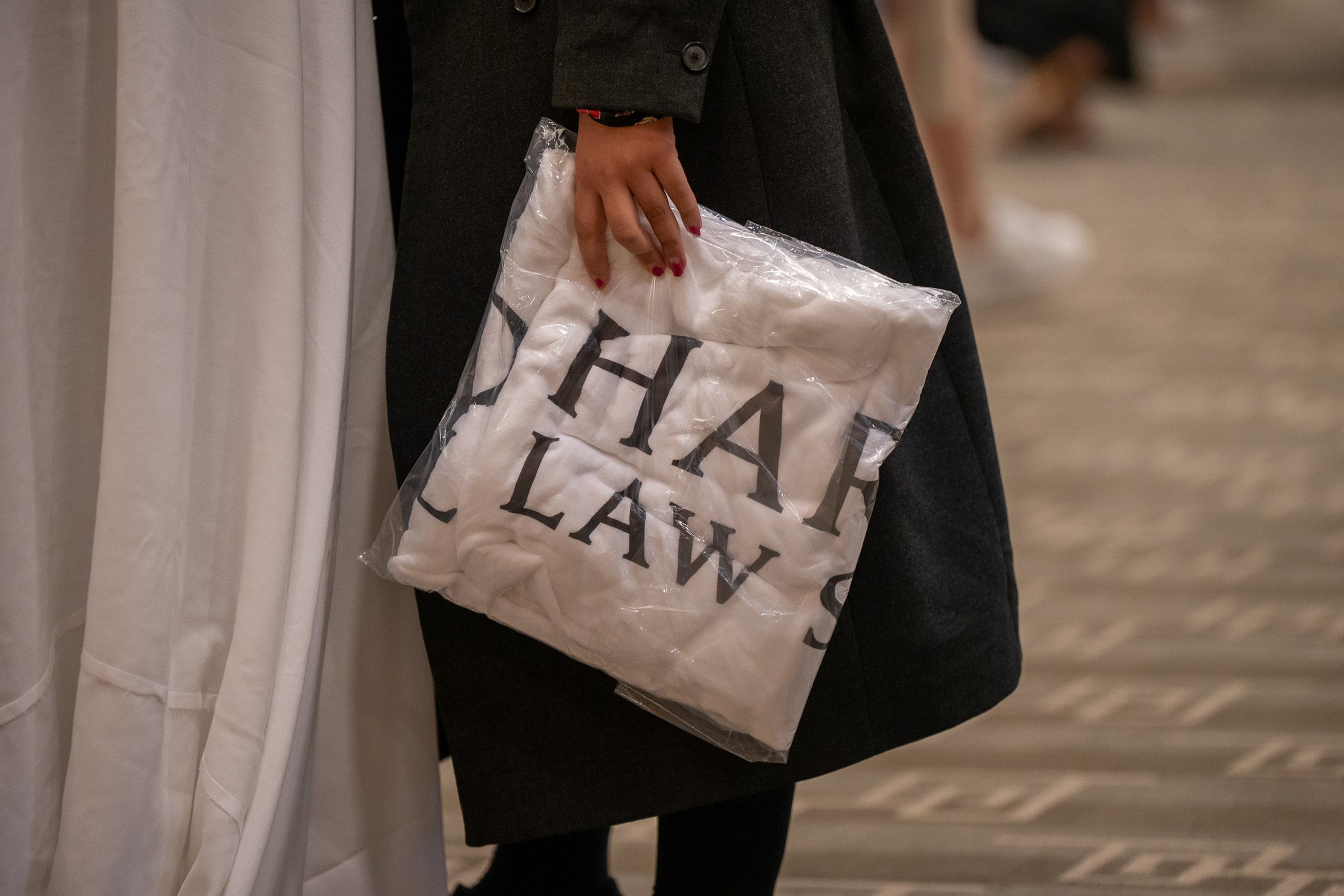 A closeup of a clear plastic package containing a white banner printed with the words Harvard Law.