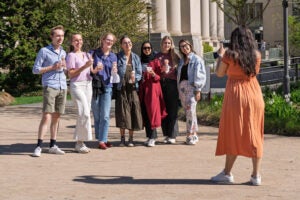 A line of students holding ice cream cones on campus pose for a cell phone photo.