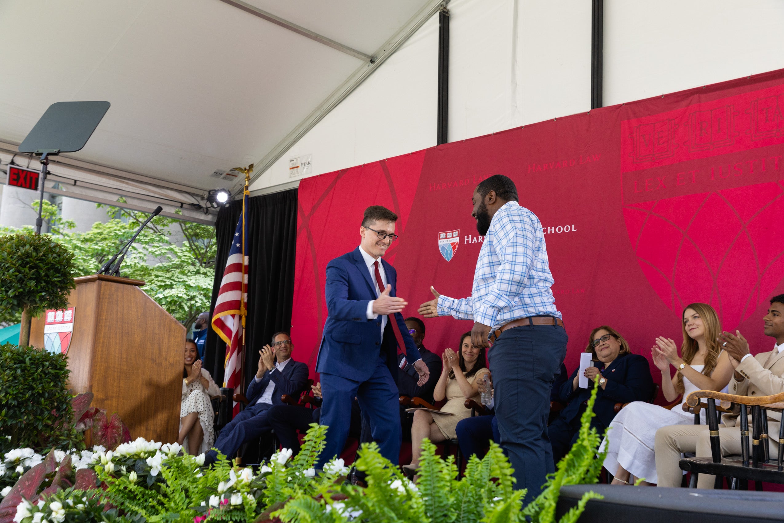 Two men greet each other on stage