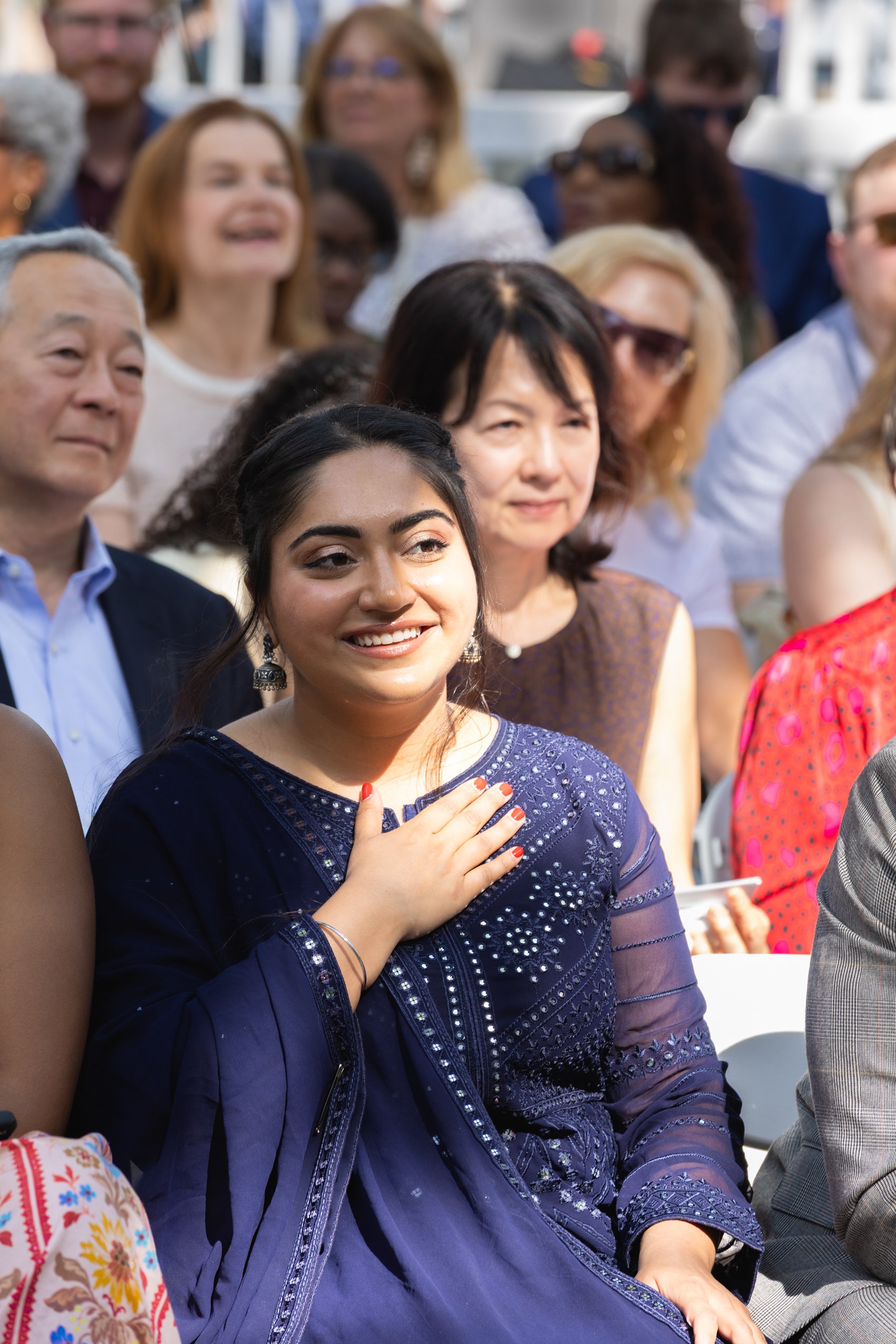 A woman sitting in the audience holds her hand over her heart.