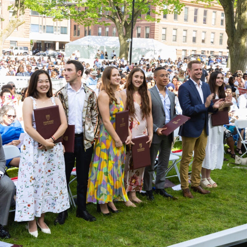A group of people standing up in a row in the front of an audience.