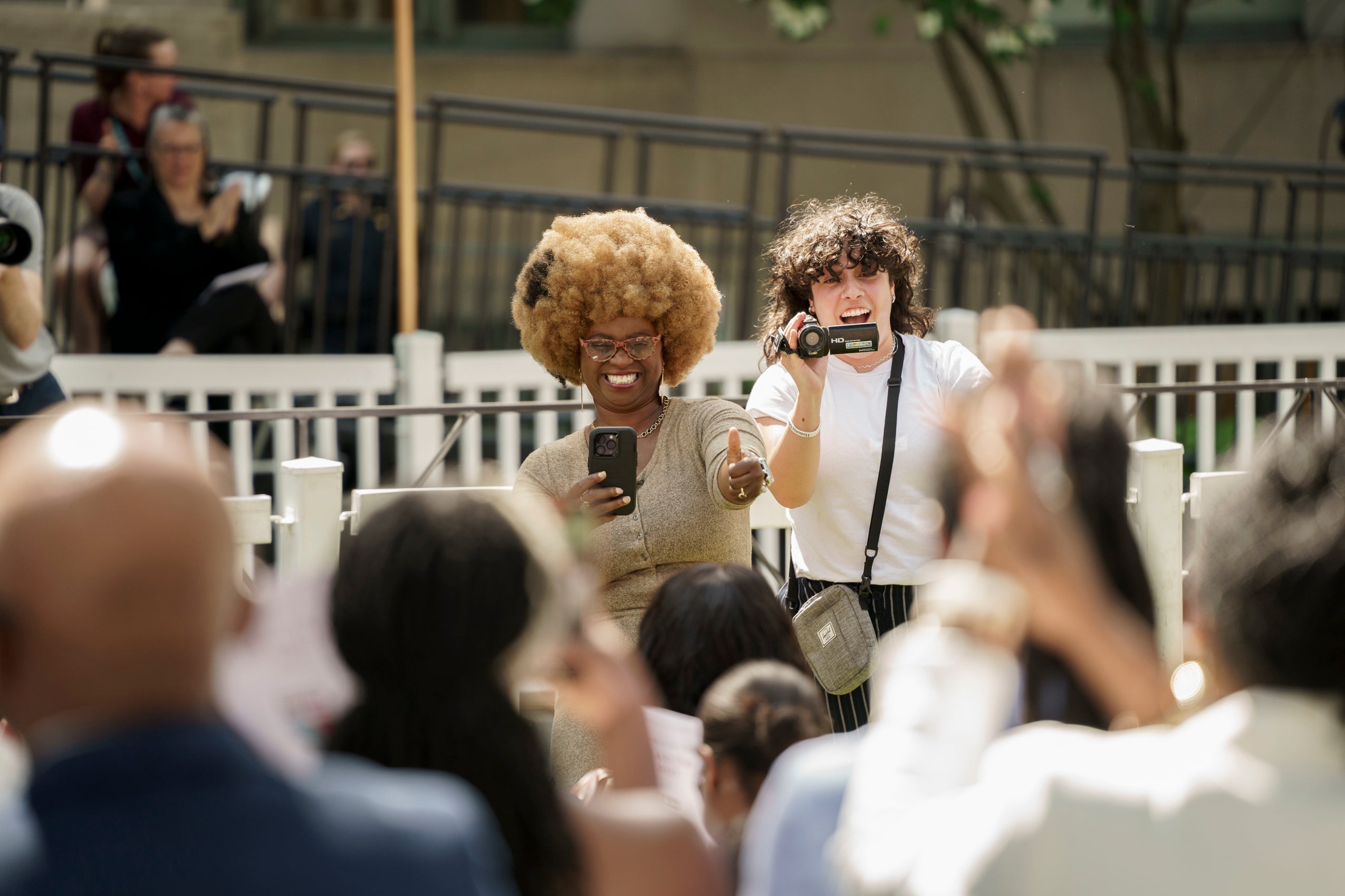Two people taking photos and video, smiling.