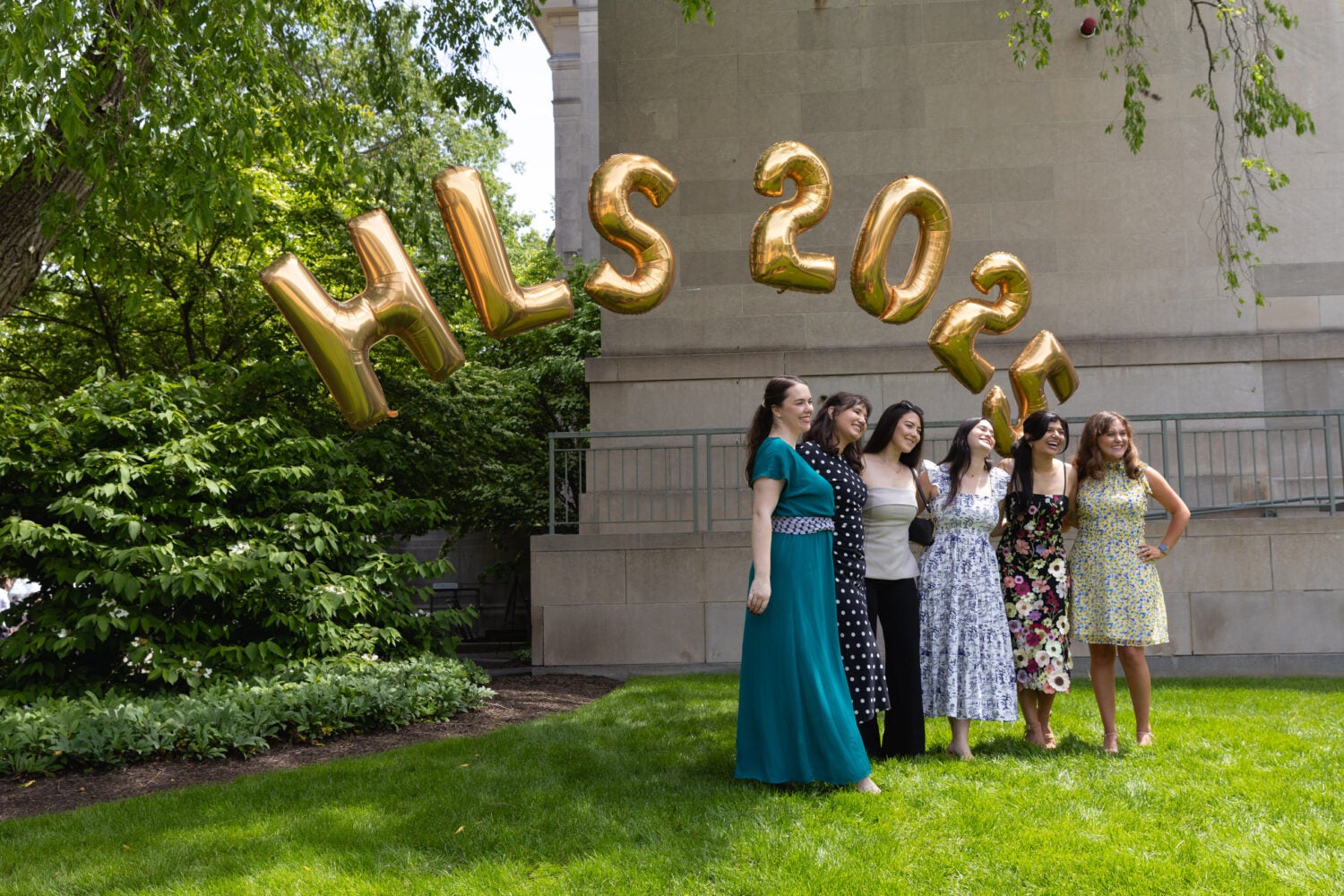 A group of six women pose under golden Harvard Law School balloons.