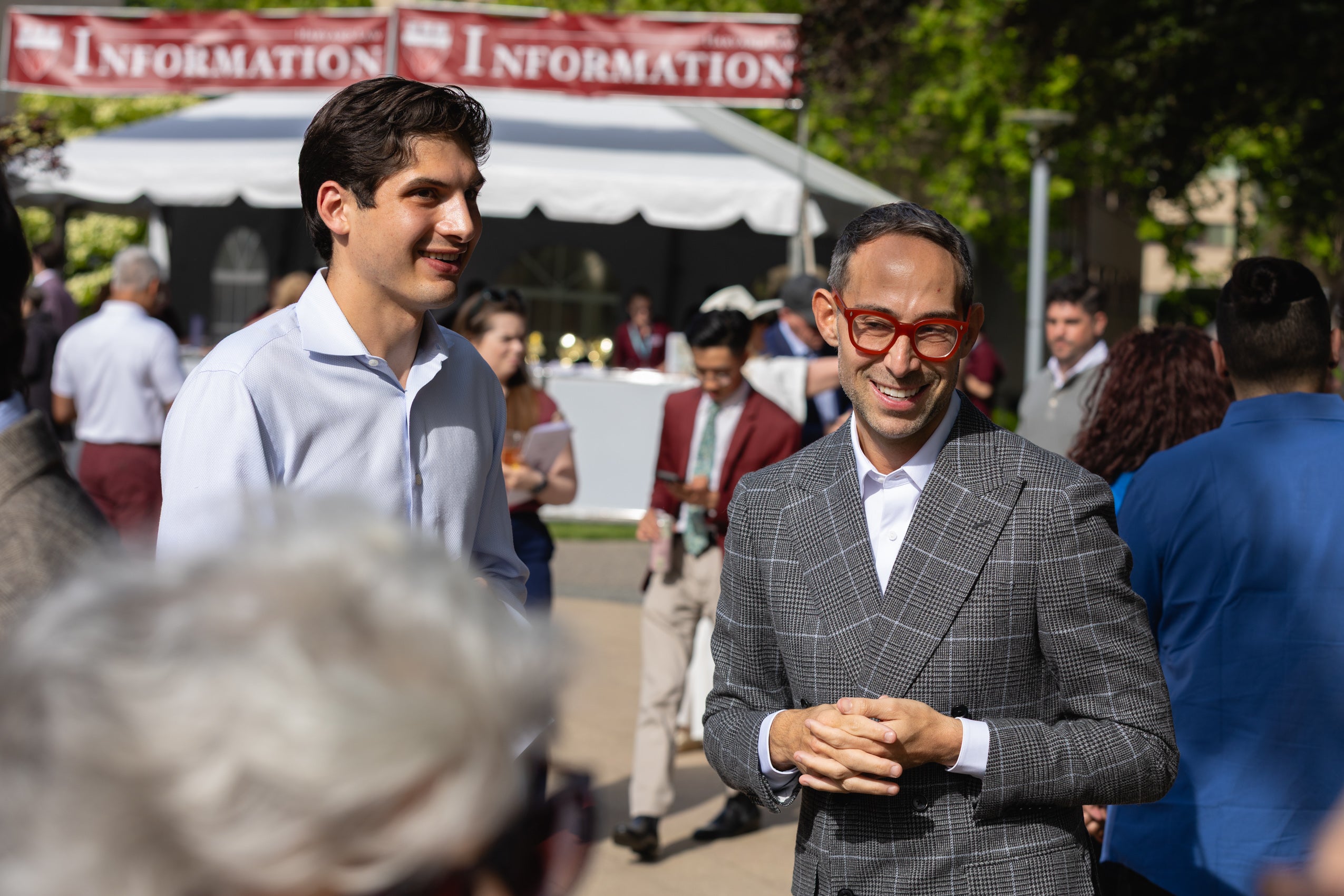 Two men chat at an outdoor reception.