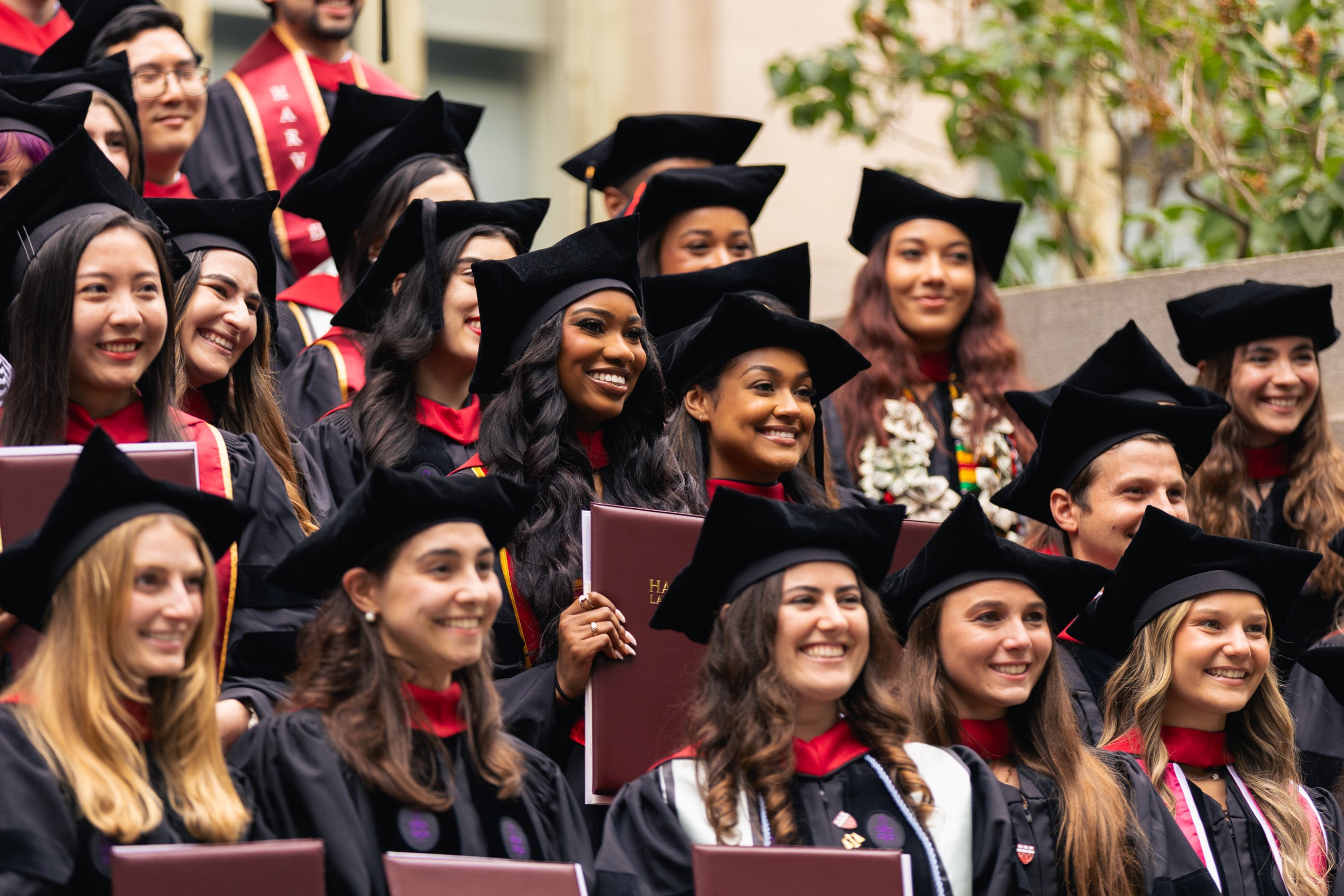A group of graduates smile for a picture with their diplomas.