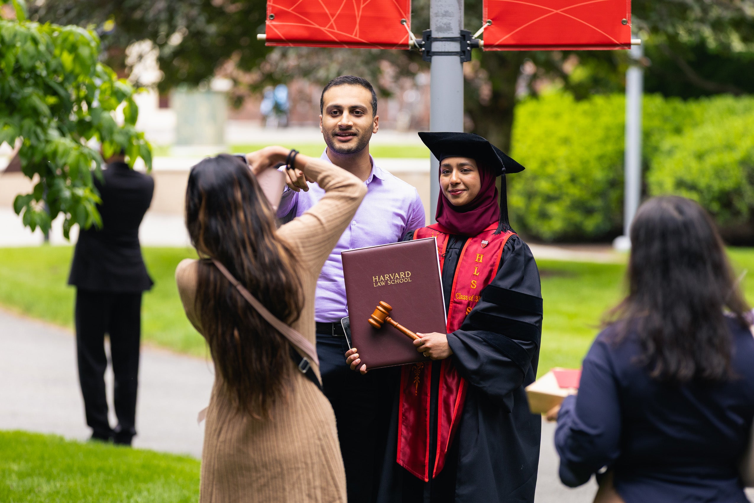 A graduate posing with a family member as another takes a photo