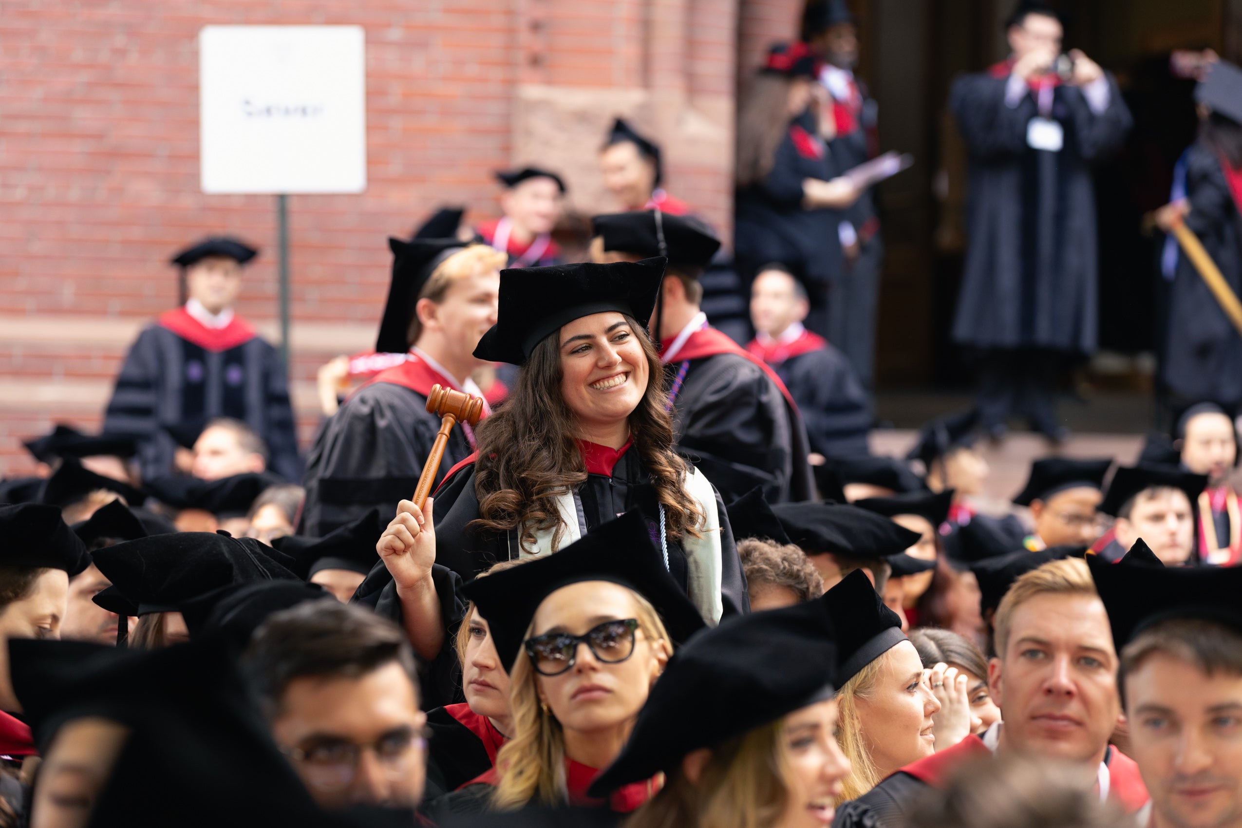 A graduating student standing and smiling with her gavel