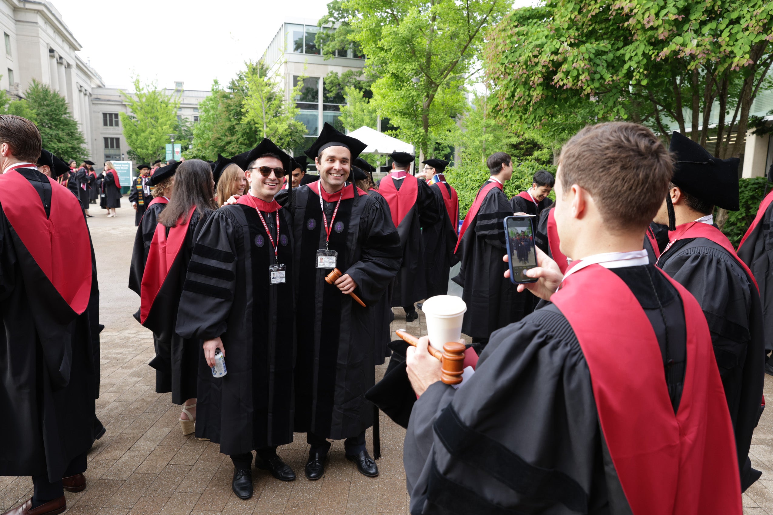 Two graduates posing together while a third graduate takes a photo