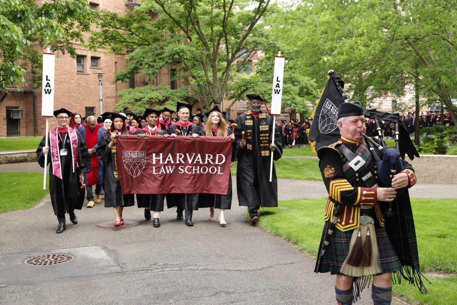 Class marshals and bagpiper lead procession