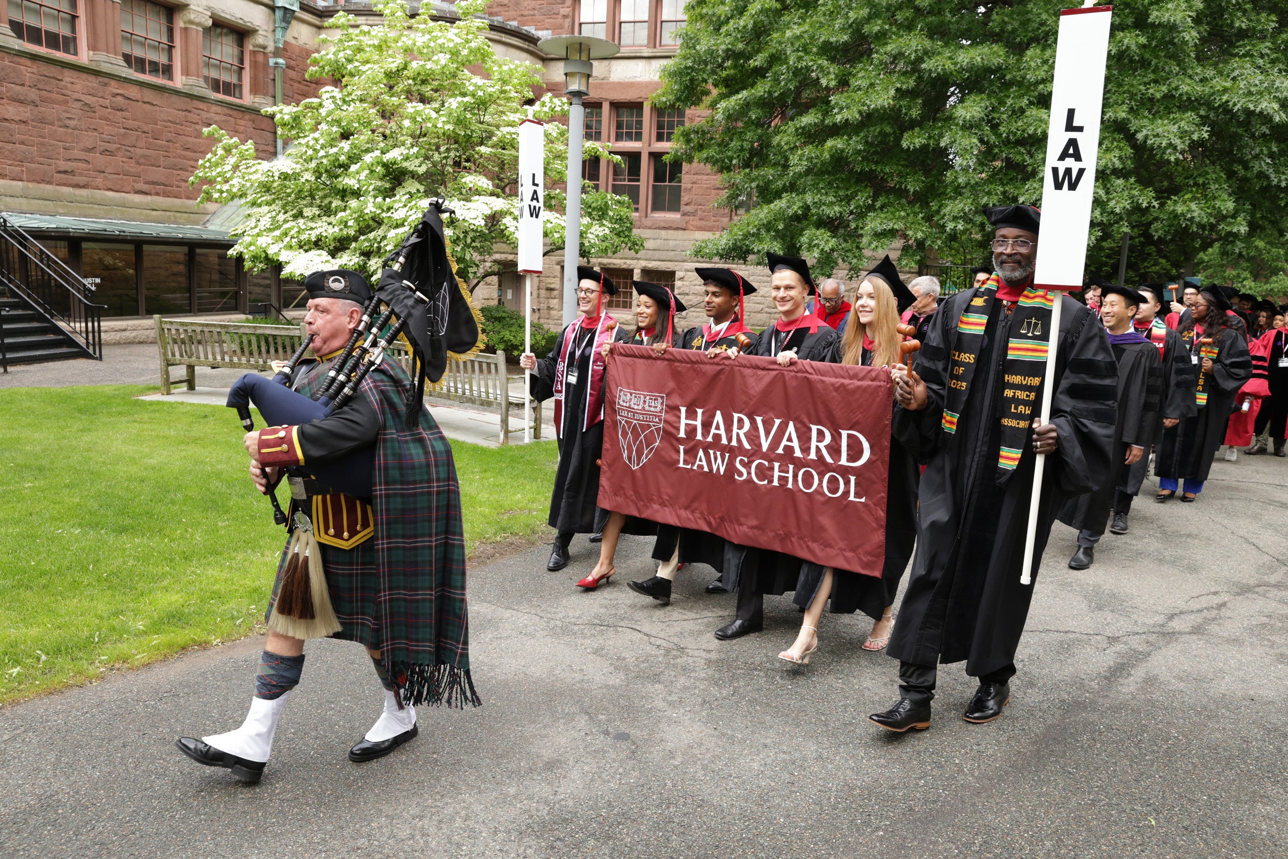 Class marshals and bagpiper lead procession