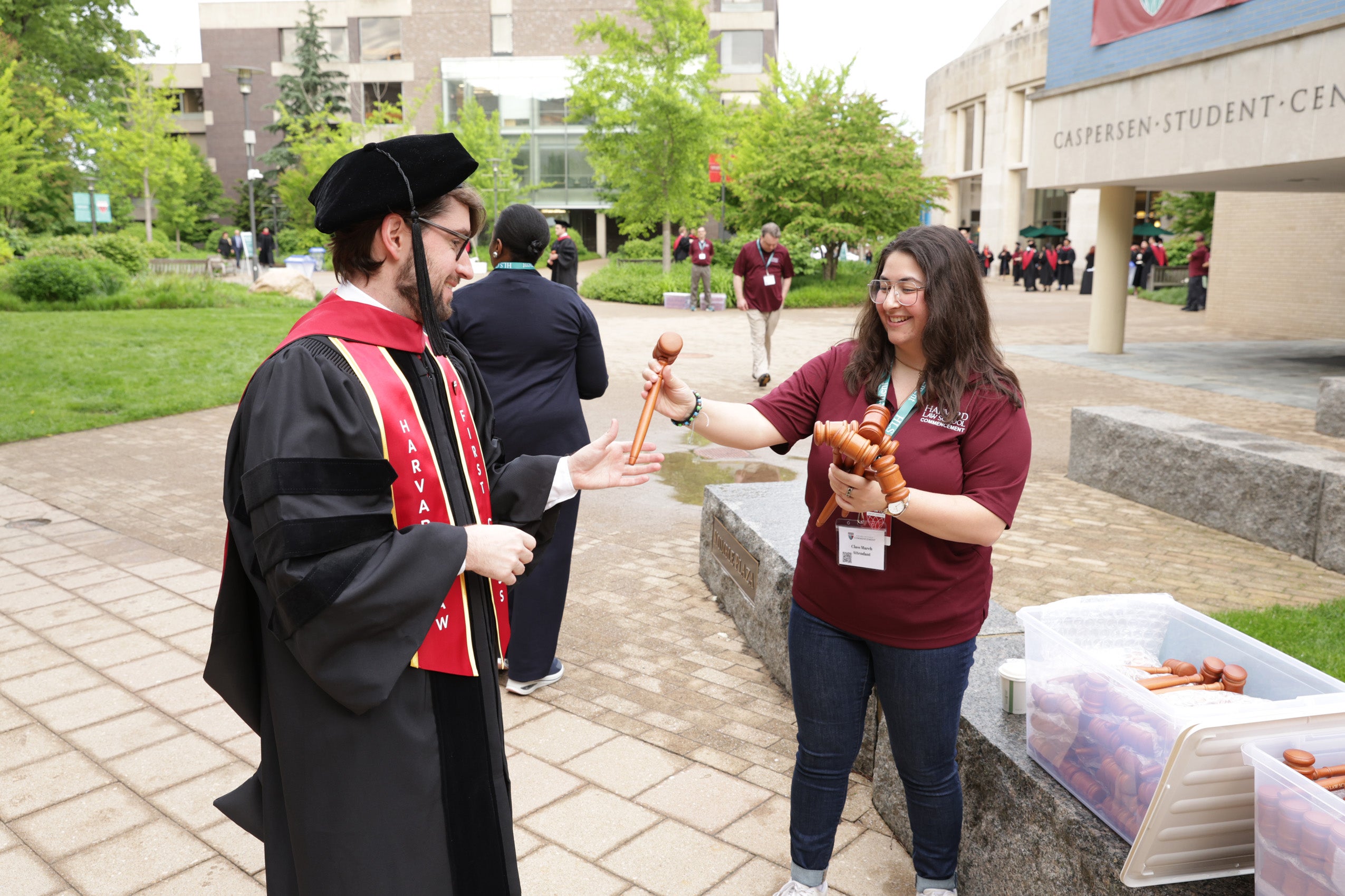 A Harvard Law School staff member hands a graduate a gavel.