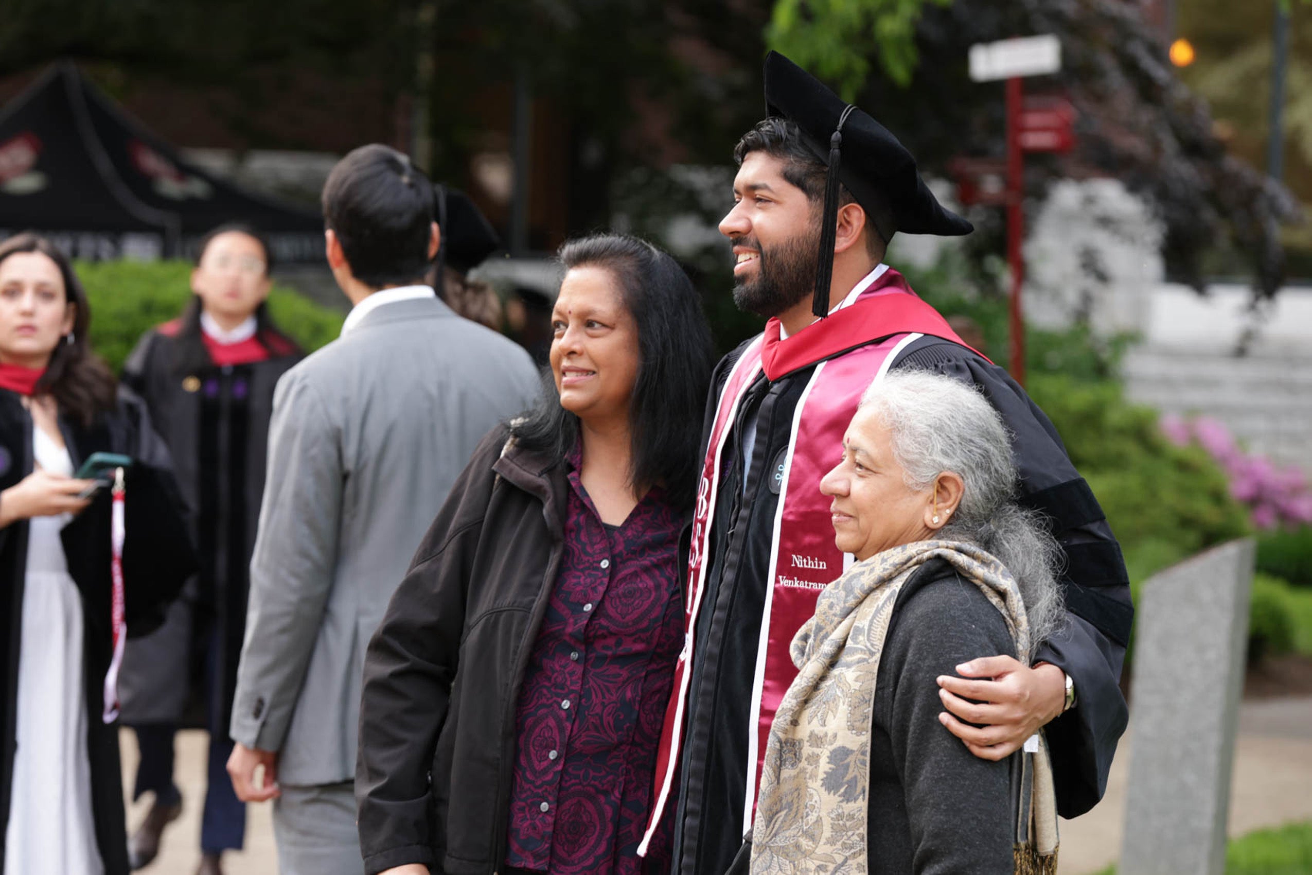 A graduate in regalia poses with his family