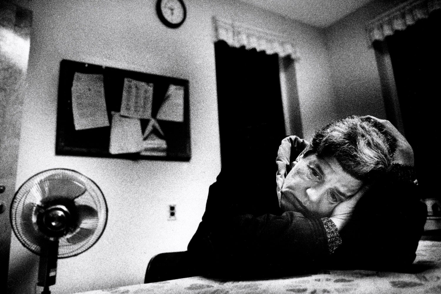 Black and white image of a woman with her head down on a table.