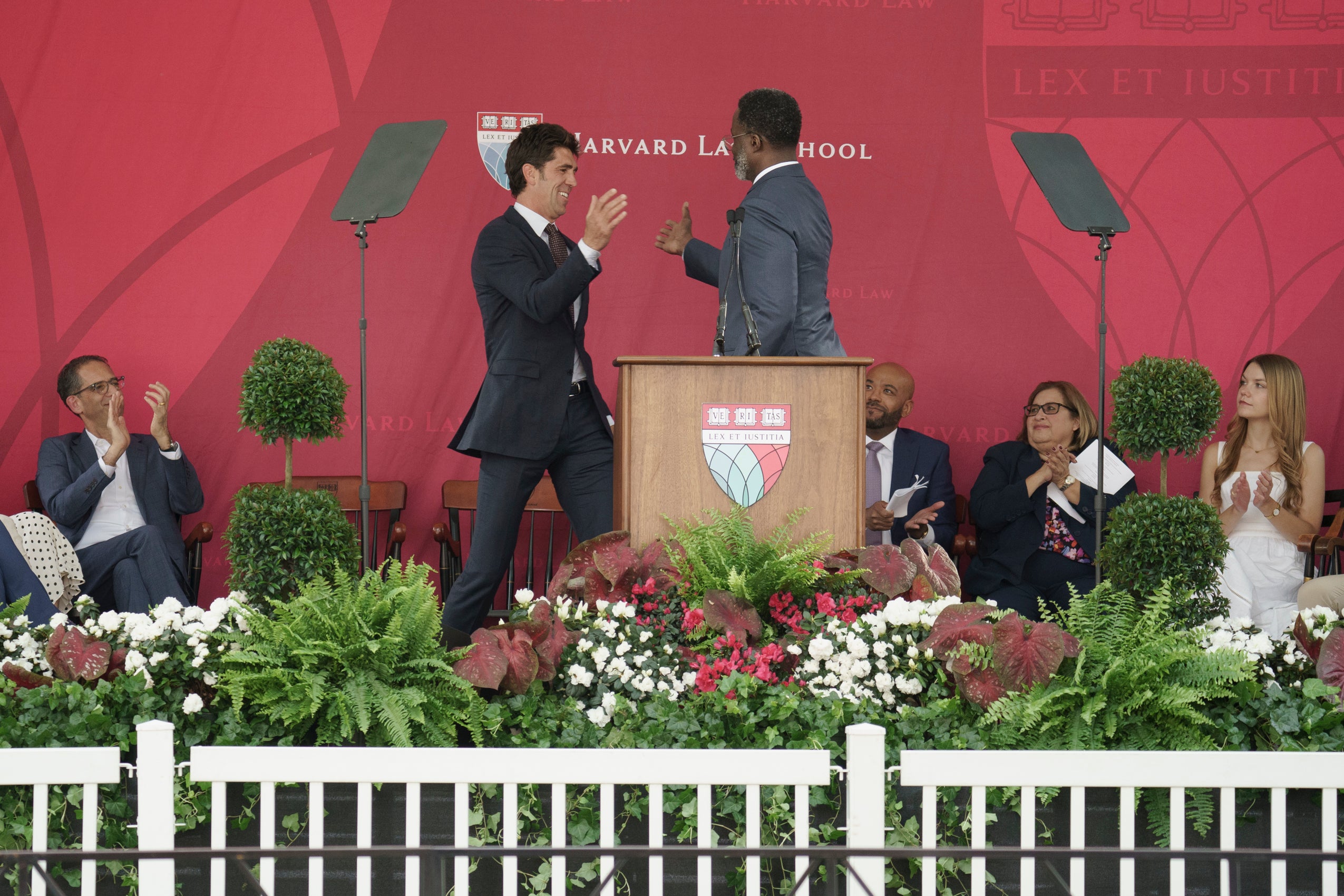Two men greeting each other behind a podium