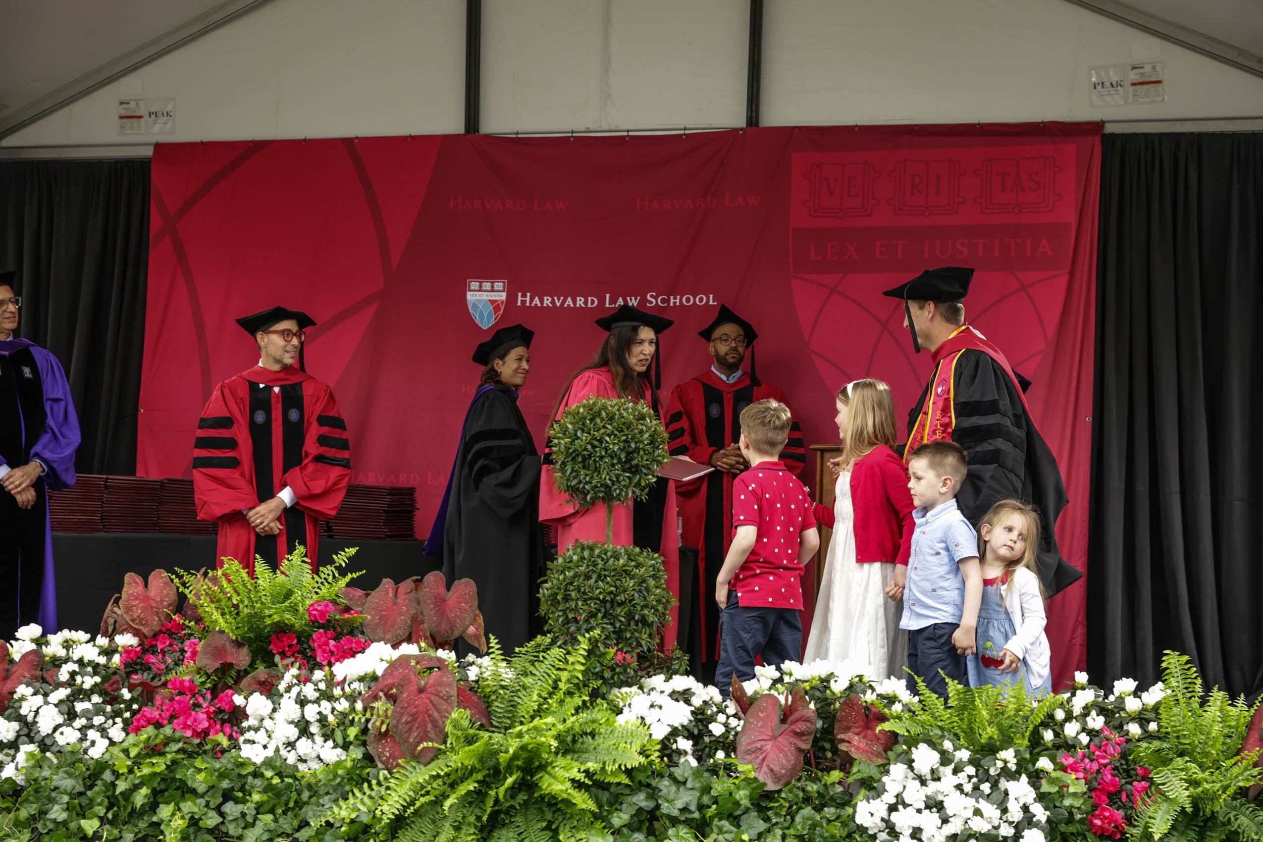 A graduate and his children on stage receiving his diploma